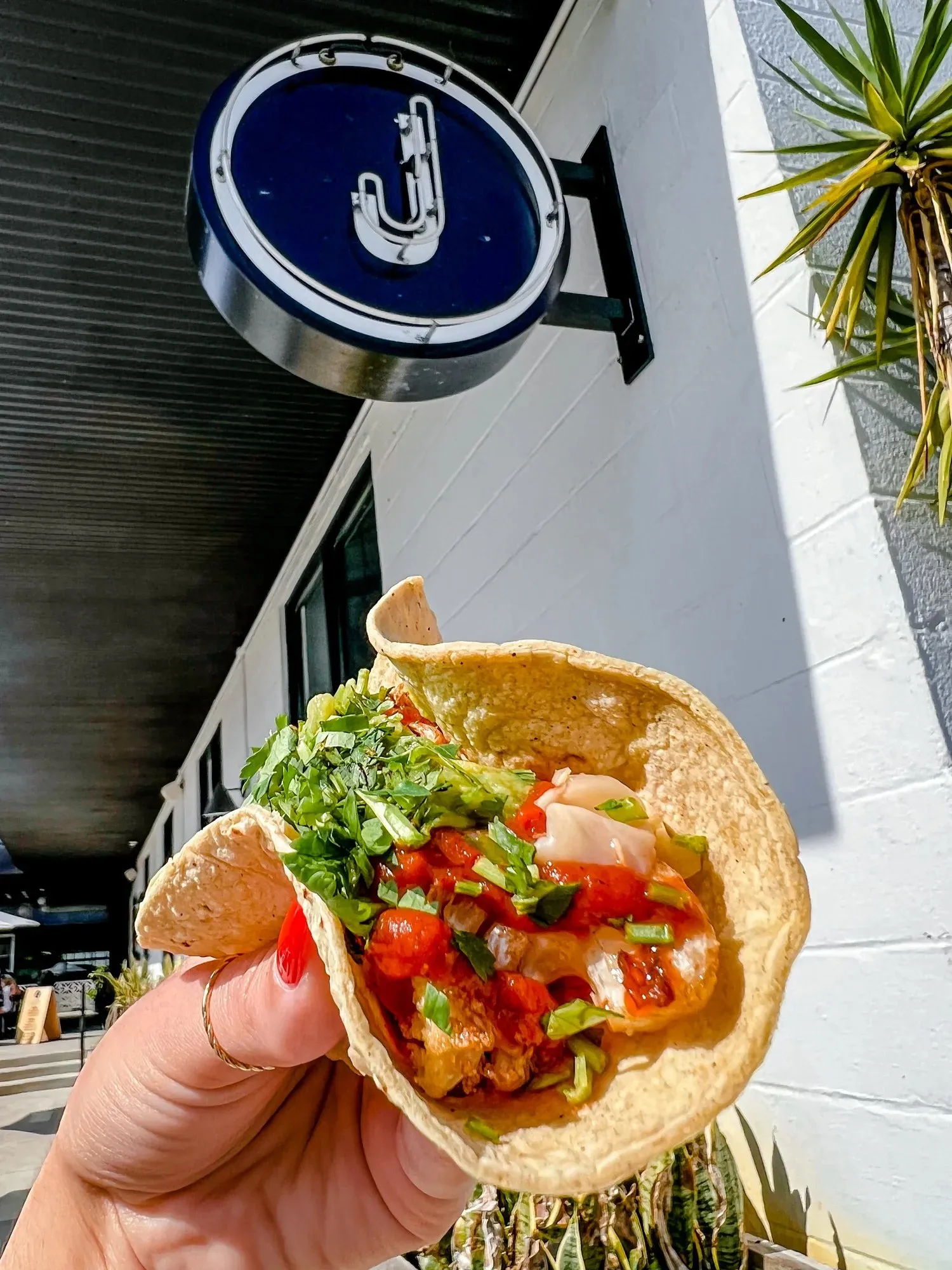 A taco topped with salsa held up outside The Joinery in Lakeland
